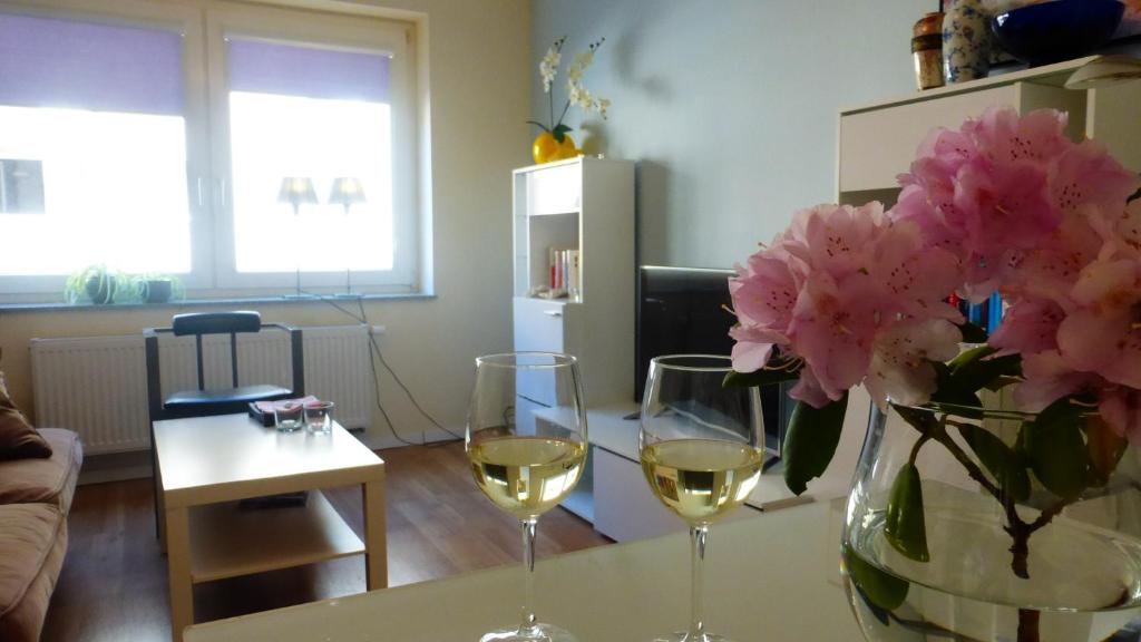 two glasses of wine and a vase of flowers on a table at Kleines Studio Albatros in Bremerhaven