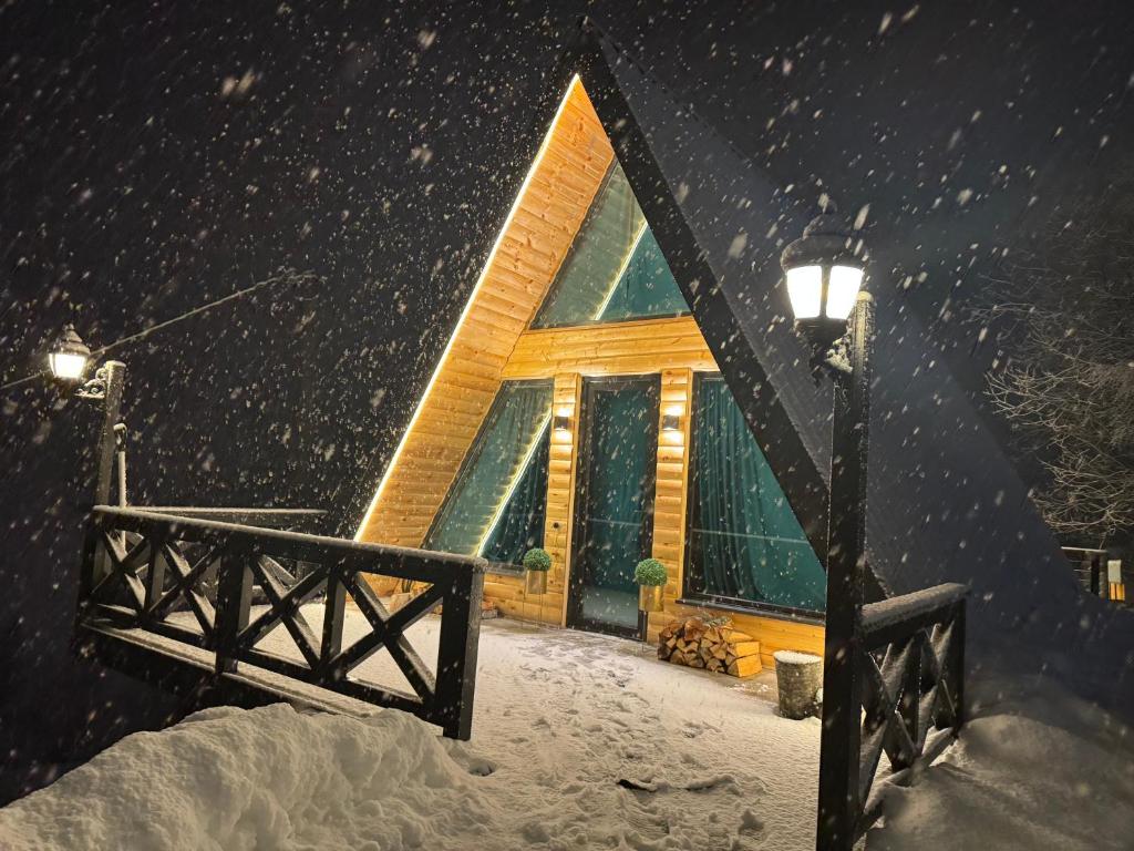una cabaña de madera en la nieve con luz de la calle en AMO en Gudauri