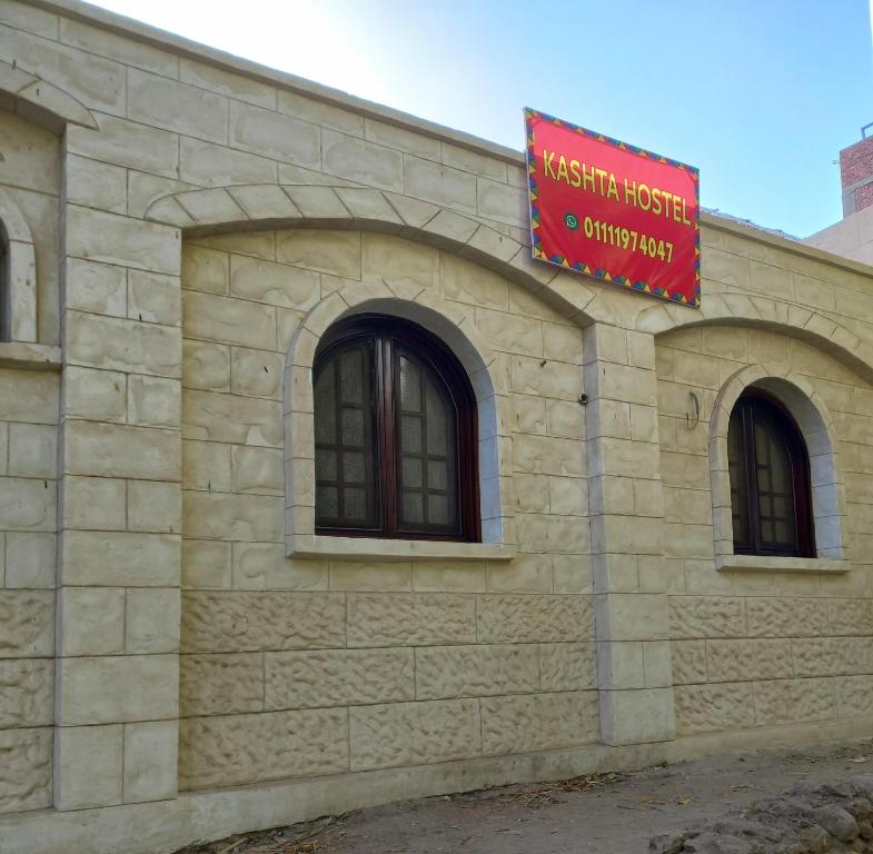 un edificio de ladrillo con una señal roja. en Kashta Guest House & Hostel, en Asuán