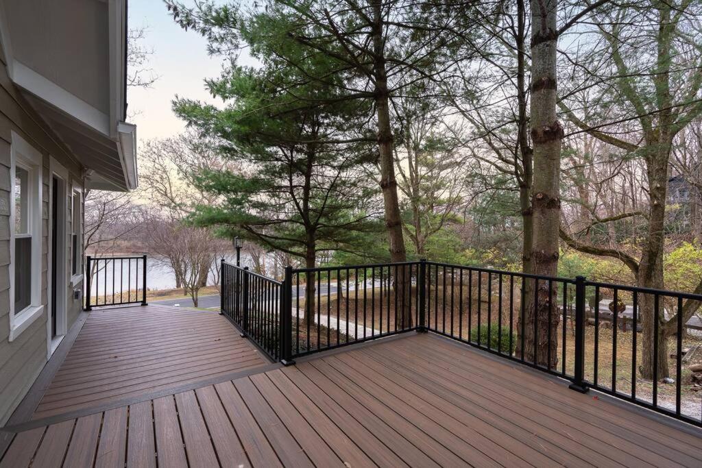 a wooden deck with a black fence and trees at Riverside Retreat! in West Lafayette