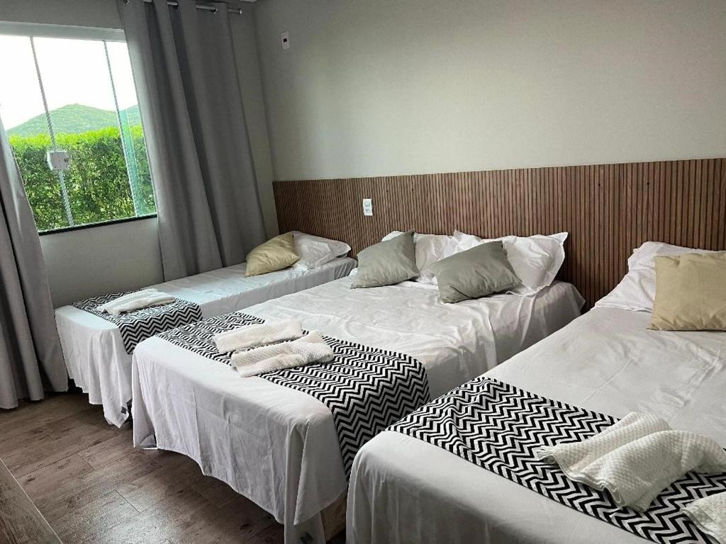 3 Betten in einem Zimmer mit Fenster in der Unterkunft Cantinho da Alegria Suítes in Capitólio
