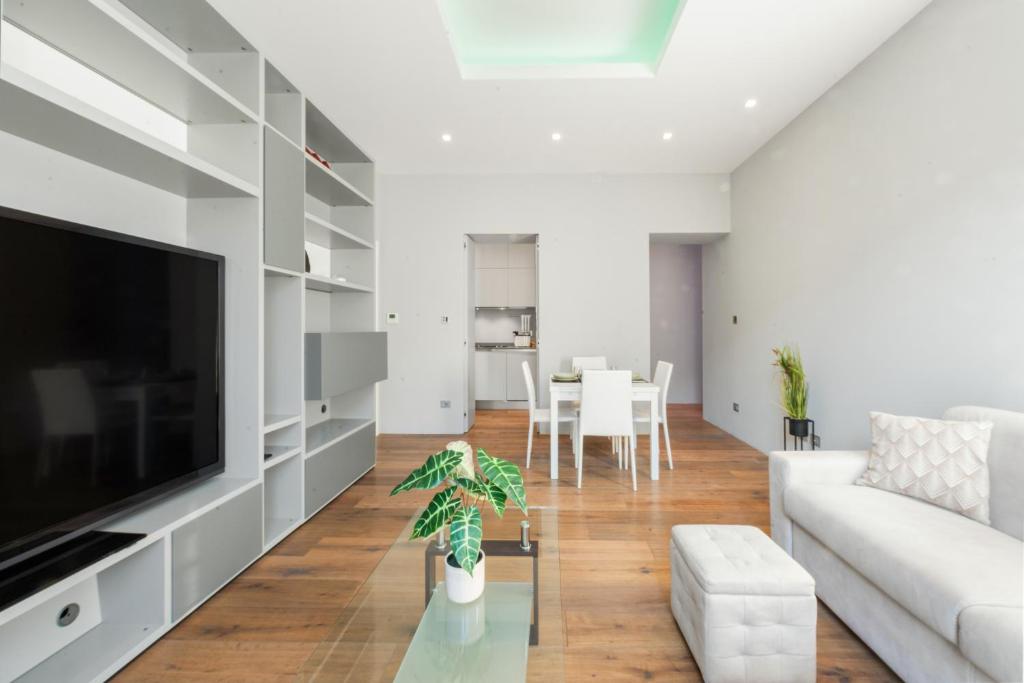 een woonkamer met witte meubels en een flatscreen-tv bij Idromassaggio Brera - 5 min Duomo in Milaan