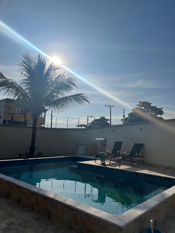 a swimming pool with two chairs and a palm tree at Casa na praia in Itanhaém