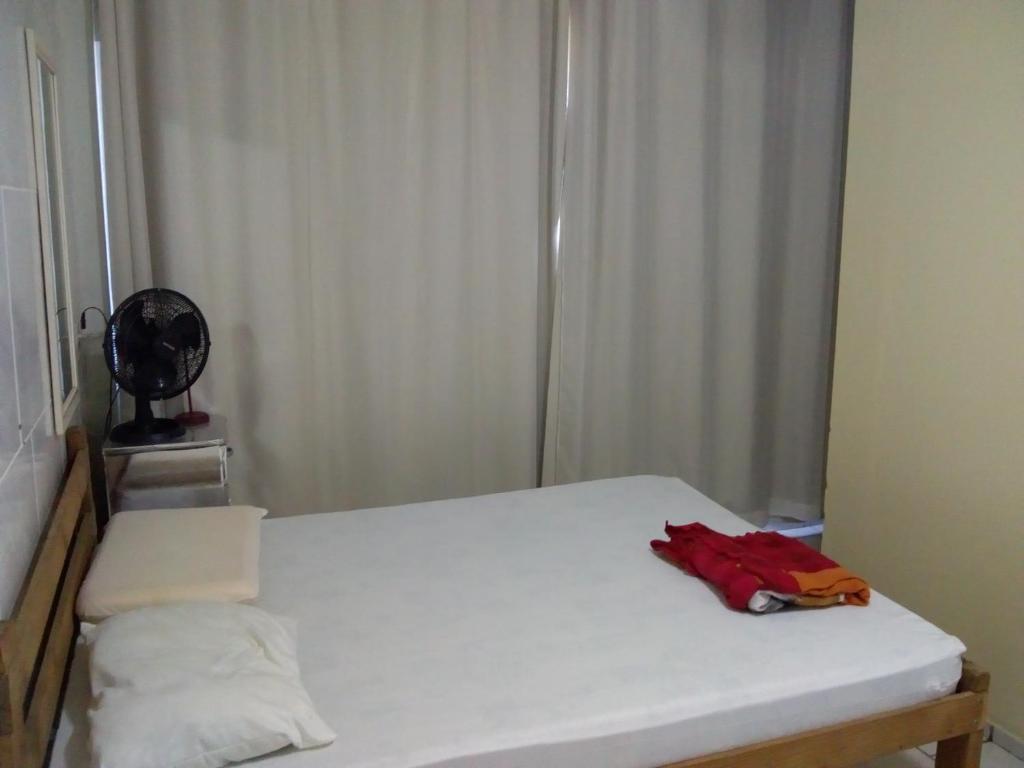 um quarto com uma cama branca com um item vermelho em AP praia Itaguaçu São Chico em São Francisco do Sul