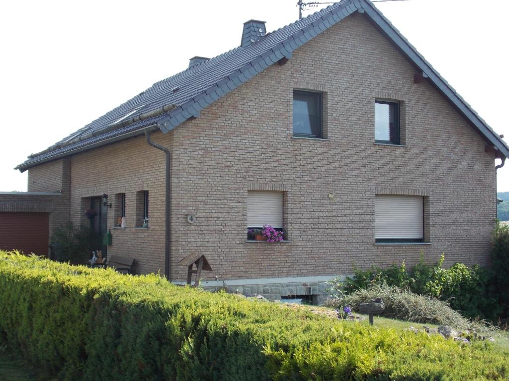 a brick house with a hedge in front of it at Ferienwohnung Inge Blum in Müllenbach
