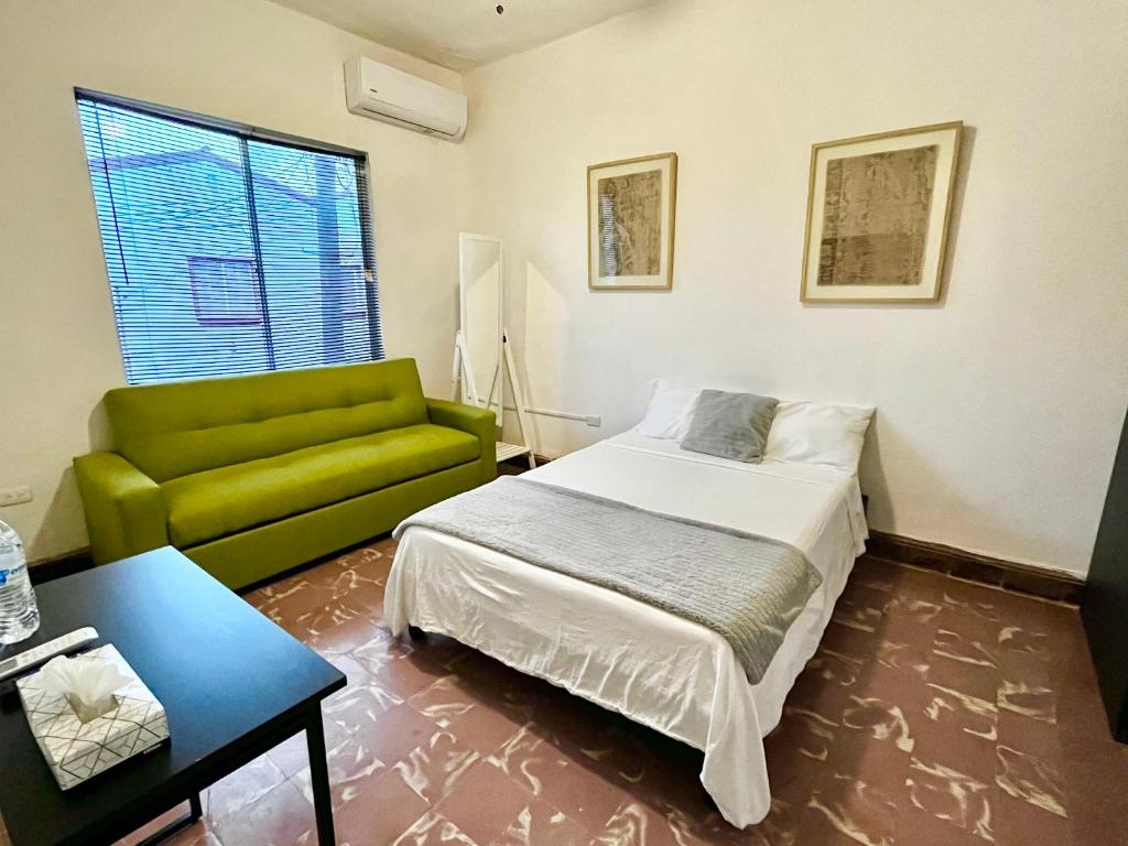 1 dormitorio con 1 cama y 1 sofá verde en Confortable Loft MN 960 E Centro Mty cerca de todo, en Monterrey