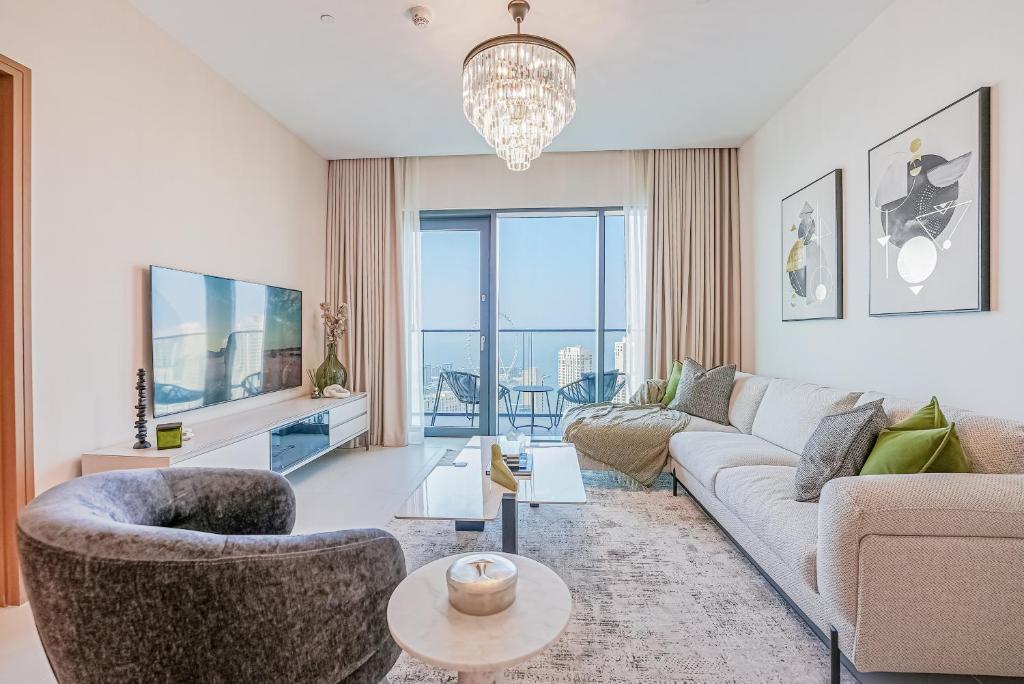 Modern 2BR High Floor Haven in Vida Dubai Marina في دبي: غرفة معيشة مع أريكة وتلفزيون
