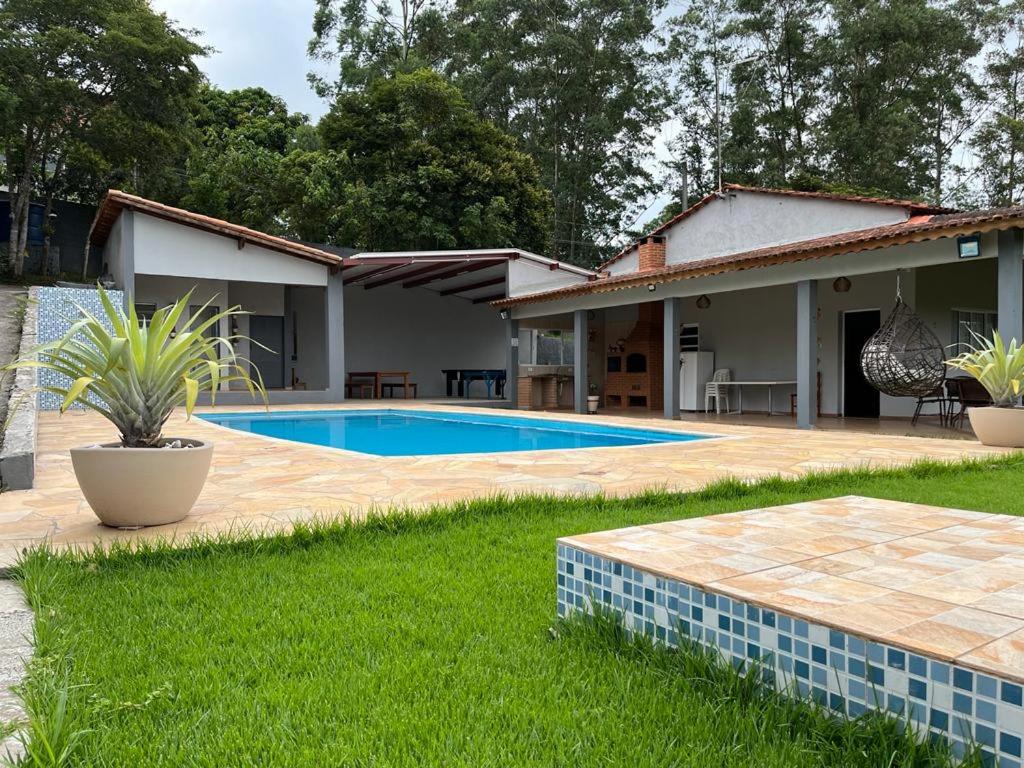 a house with a swimming pool in the yard at Chácara em Alpes de Mairiporã in Mairiporã