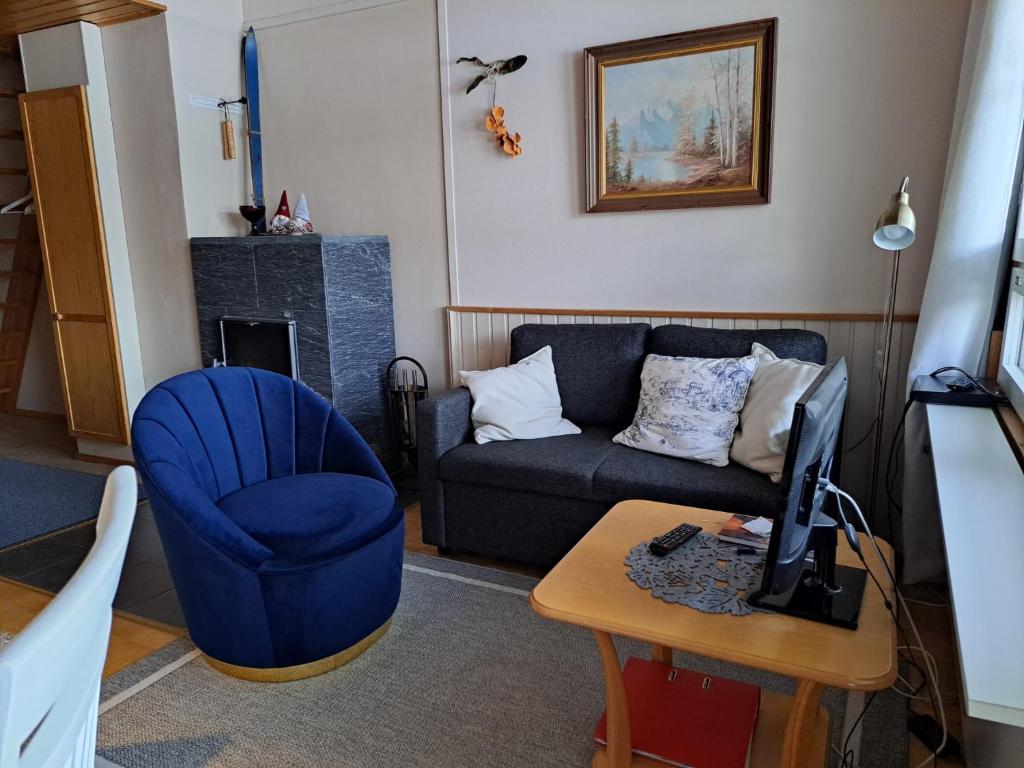 a living room with a couch and a blue chair at Rivitalon huoneisto Tahkolla in Tahkovuori
