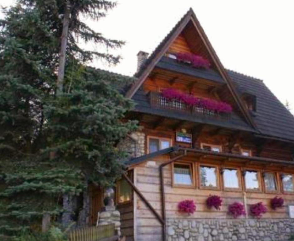 a large wooden house with flowers on the balcony at Bukovina Concept Mountain in Bukowina Tatrzańska