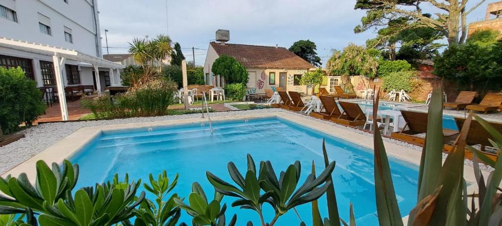 una piscina con sillas y una casa en Hotel Solyma en Santa Teresita