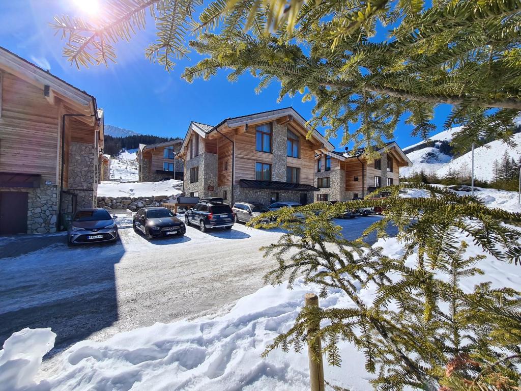 una casa en la nieve con coches aparcados en la entrada en CHALET ASKALA JASNÁ en Demanovska Dolina