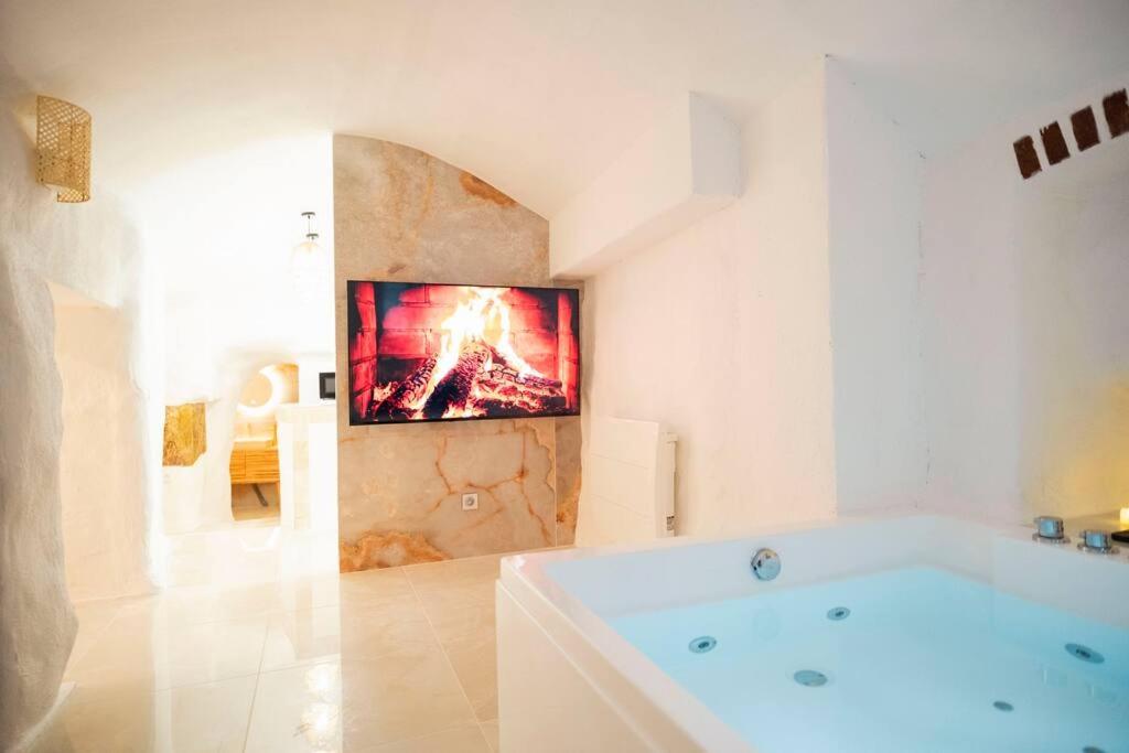 a white bathroom with a bath tub and a painting on the wall at Le temple d'Aphrodite, Appartement avec SPA in Vienne
