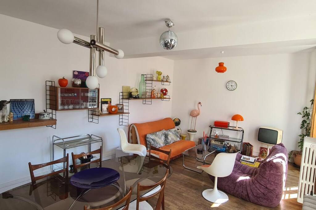 a living room with a couch and chairs and a tv at Appart 70s au cœur du Perche in Rémalard en Perche
