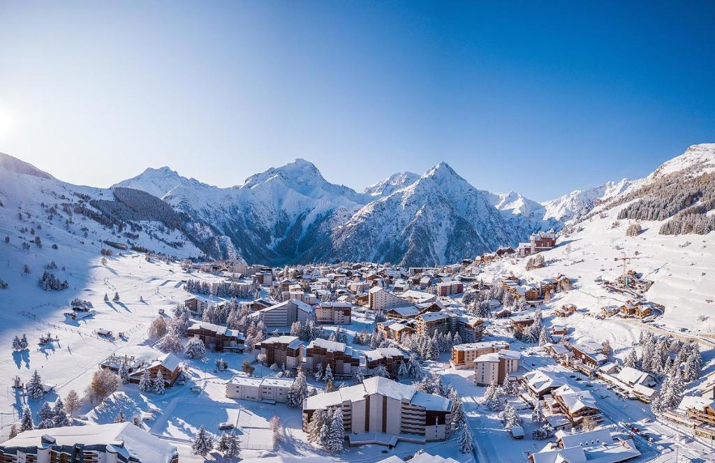 une ville dans la neige avec des montagnes en arrière-plan dans l'établissement Immeuble Lauvitel - Apt Comme à la Maison- Front de Neige Plein Sud, à Les Deux Alpes