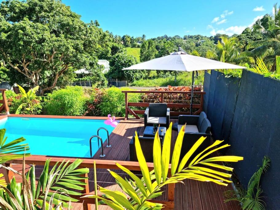 eine Terrasse mit einem Sonnenschirm und einem Pool in der Unterkunft Appartement Pyé koko in Lamentin