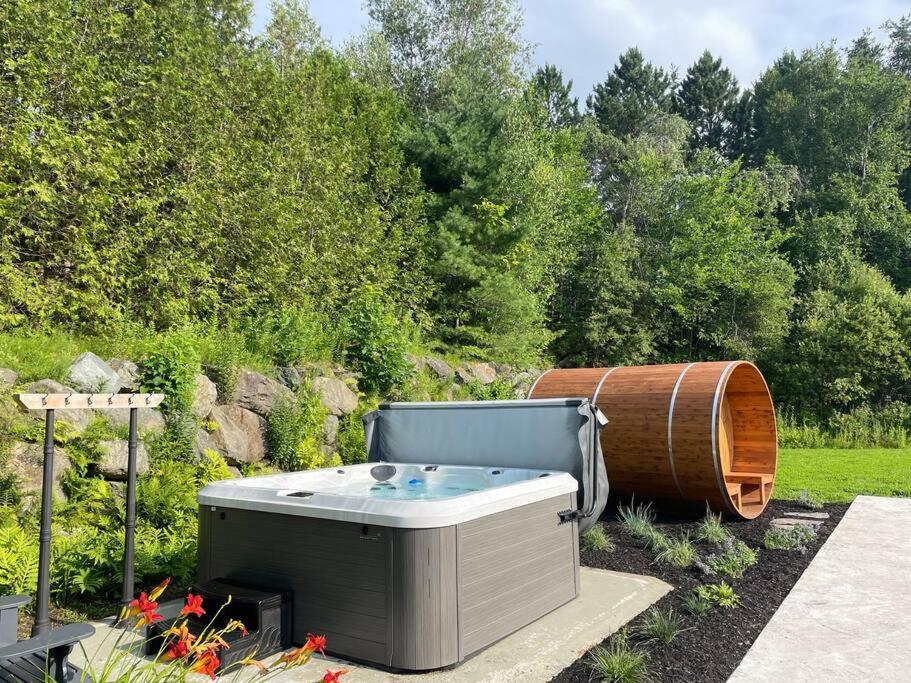 a hot tub and a barrel in a garden at Suite 212 - Destination Mont-Orford in Magog-Orford