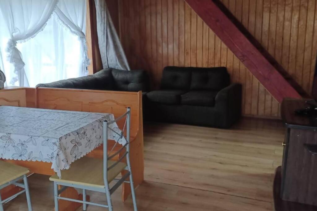 uma sala de estar com um sofá e uma mesa em cabañas mateo 01 em Puyuhuapi