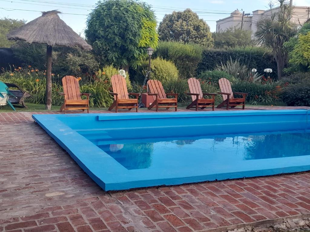 a blue swimming pool with chairs and an umbrella at Departamentos Serranos en Tandil in Tandil