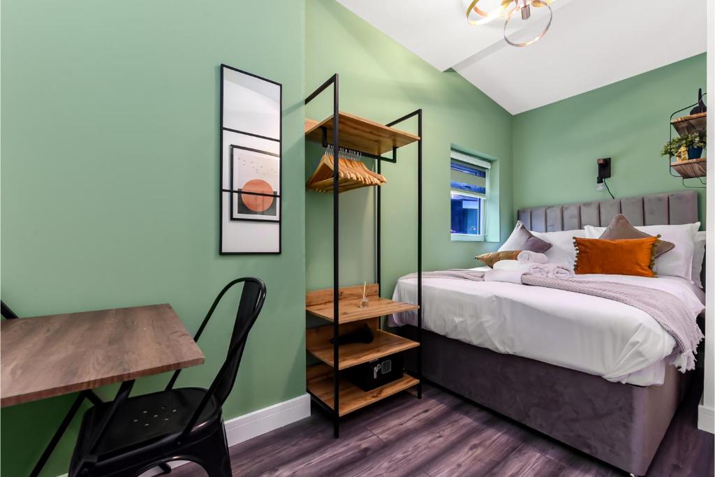 1 dormitorio con paredes verdes, 1 cama y escritorio en Fabulous One Bedroom Flat with Private Garden, en Londres