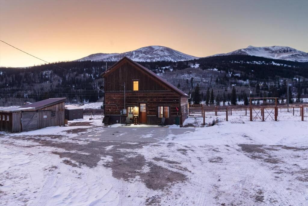 a log cabin in the snow with mountains in the background at The Bross Ranch Cabin - Open Floor Plan! 10Mi to Ski Breck! Hot Tub! in Fairplay