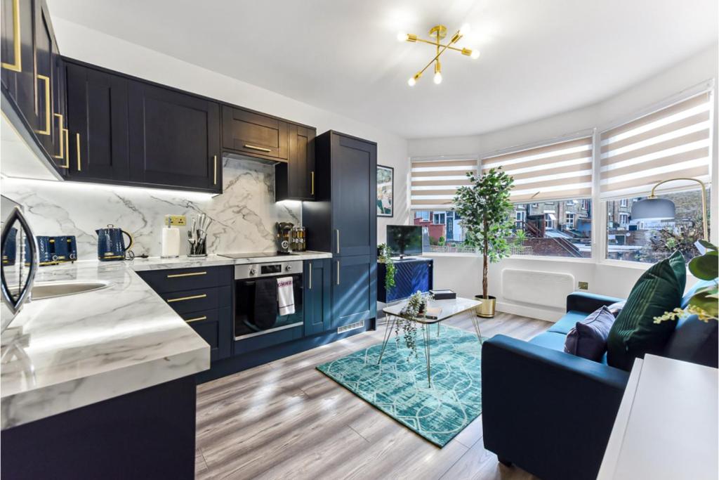 uma cozinha com armários azuis e um sofá azul em Stylish and Family Friendly 3 Bedroom Apartment em Londres
