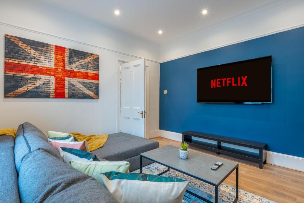 a living room with a couch and a tv on a blue wall at West London Period House in London