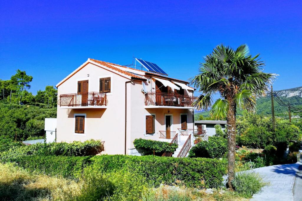 a house with a palm tree in front of it at Apartments with a parking space Vrisnik, Hvar - 8733 in Jelsa