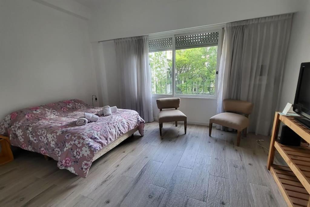 a bedroom with a bed and two chairs and a window at Departamento en glamourosa calle, 1 dormitorio in Buenos Aires