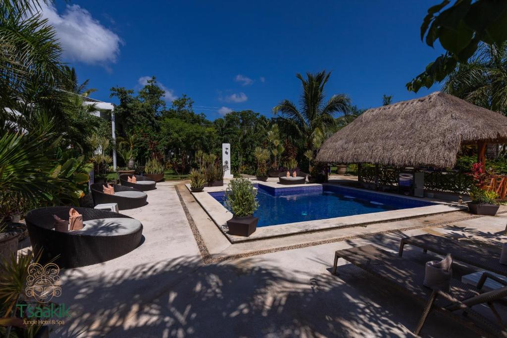 un complejo con piscina y sombrilla de paja en Tsaakik Jungle Hotel & Spa, en Cancún