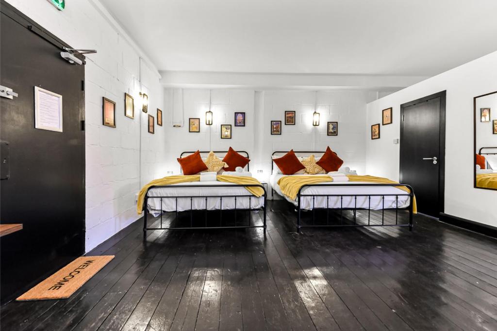 Trendy and Eccentric Flat in Hackney في لندن: سريرين توأم في غرفة بها لوحات على الجدران