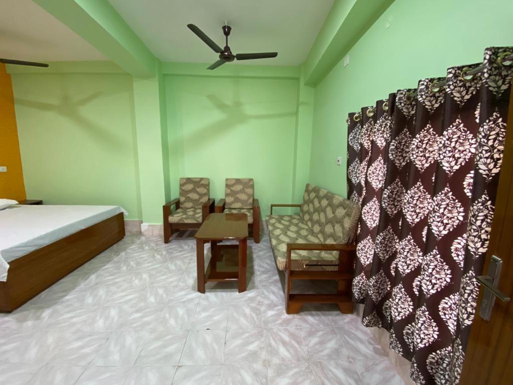 een slaapkamer met een bed en stoelen en een plafondventilator bij HOTEL RITZ in Guwahati