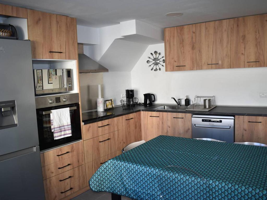 une cuisine avec des armoires en bois et une table à l'intérieur dans l'établissement Maison de Village Charmante, 3 Ch, Terrasse, à Proximité des Pistes et Commerces à Bolquère - FR-1-592-66, à Bolquère-Pyrénées 2000