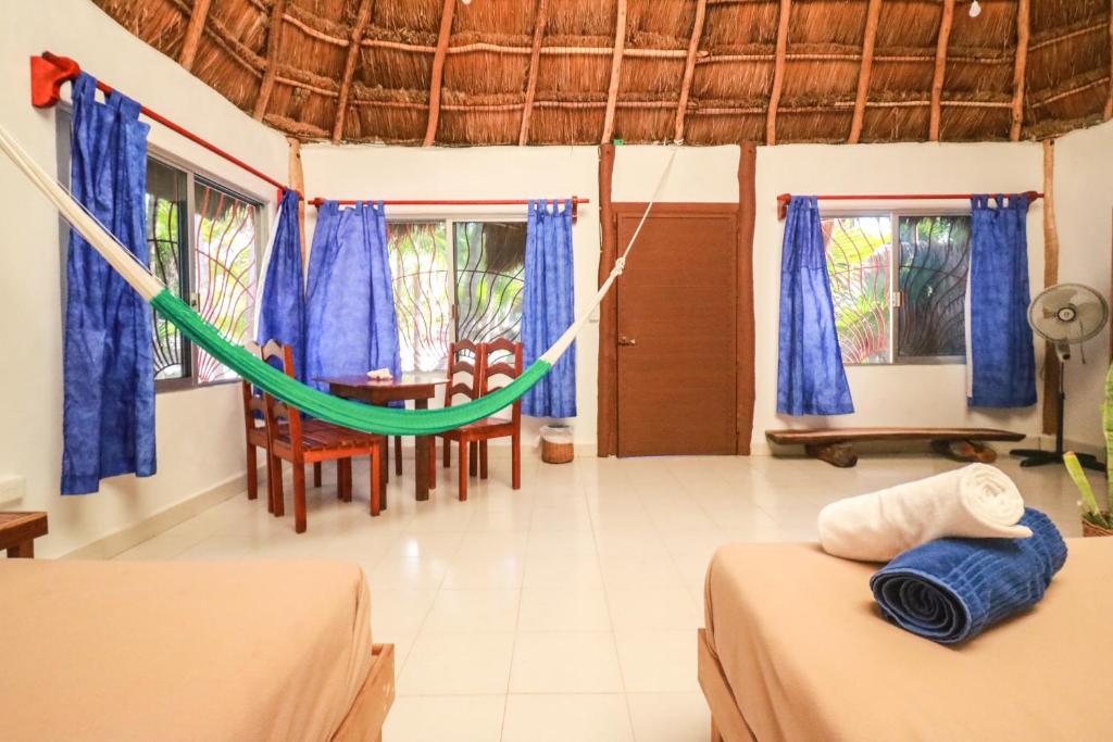 a room with two beds and a hammock in it at Playa Lakin-ha beachfront cabins in Tulum