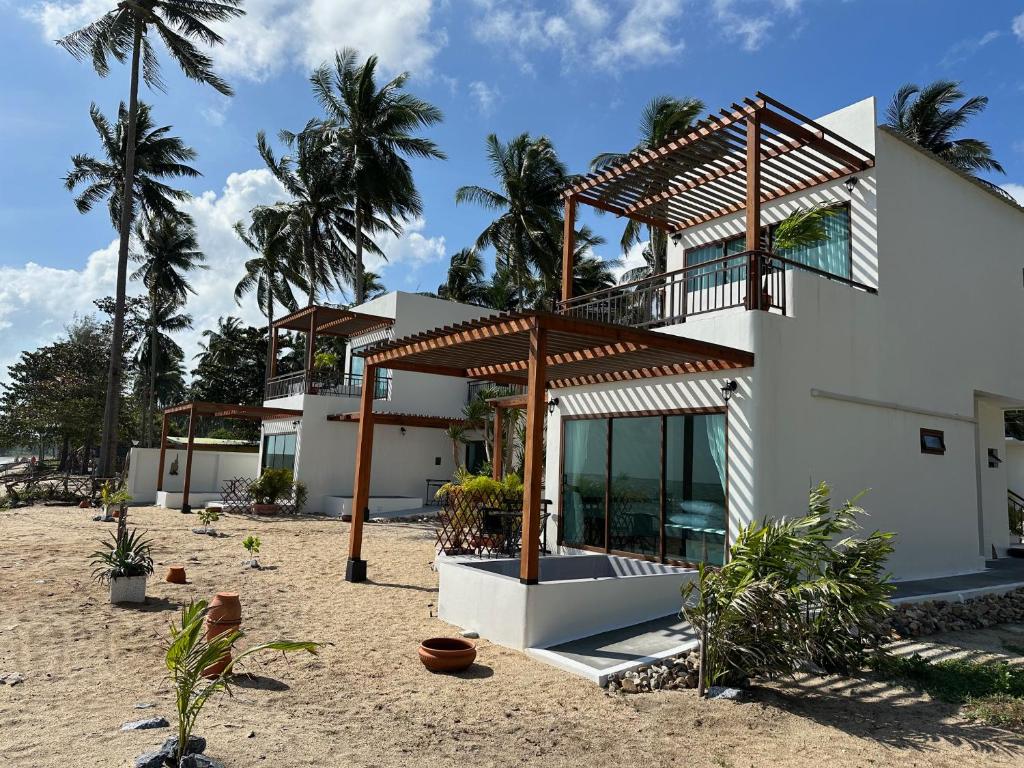 uma casa na praia com palmeiras em Chansi Beachresort em Tha Sala