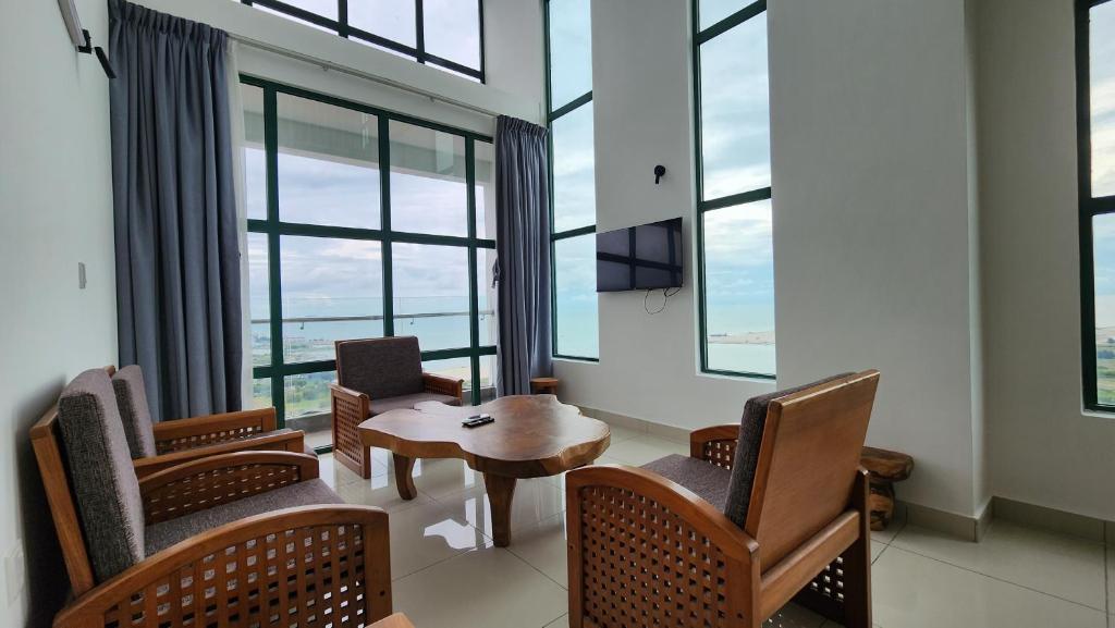 a room with chairs and a table and windows at The Suites SGR Melaka in Melaka