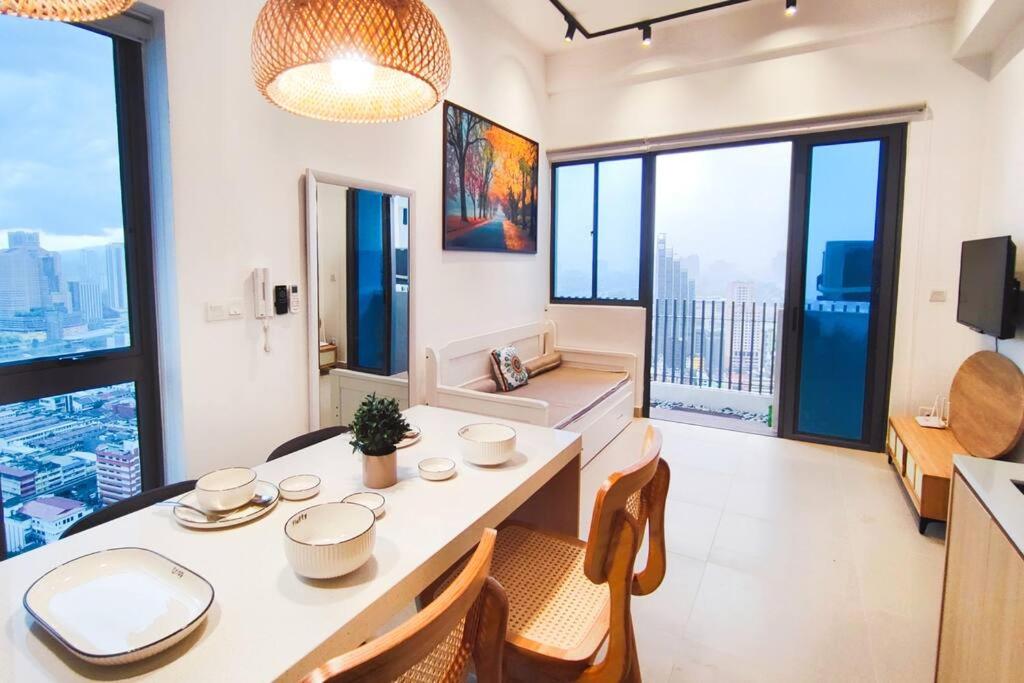 ein Esszimmer mit einem Tisch und Stühlen sowie großen Fenstern in der Unterkunft Nordic Apartment, KLCC ZenSuites in Kuala Lumpur