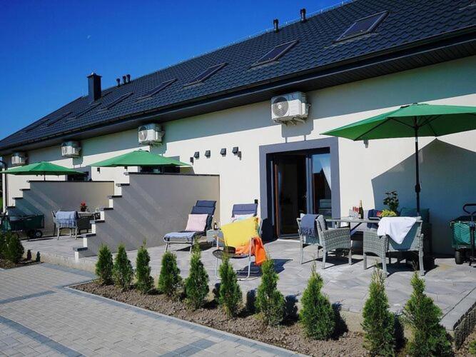 a building with a patio with chairs and umbrellas at Terraced house for 5 people, Mielenko in Mielenko