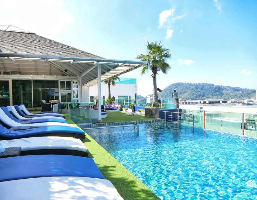 una piscina de hotel con tumbonas azules y blancas en Sira Grande Hotel & Spa, en Patong Beach