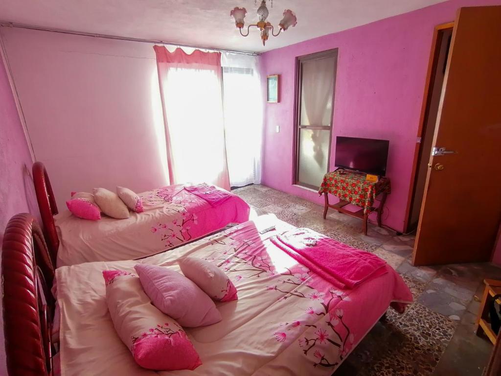 2 camas en una habitación con paredes rosas en La Carreta Rica, en Zitácuaro