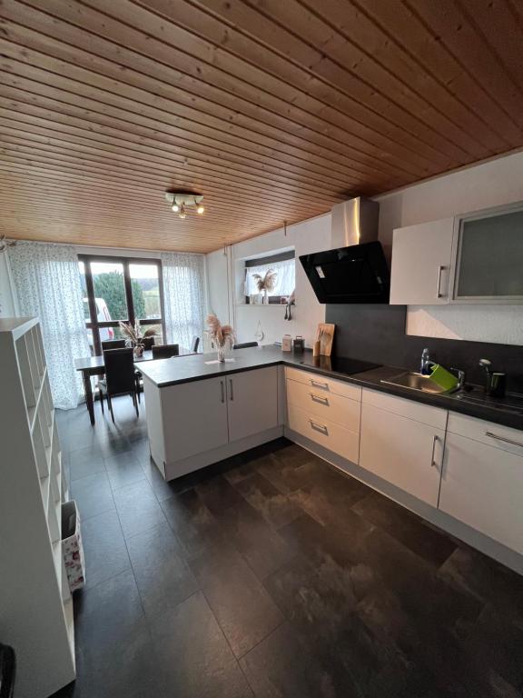 a kitchen with white cabinets and a table in it at Ferienwohnung beim Pferdehof in Neuenstein