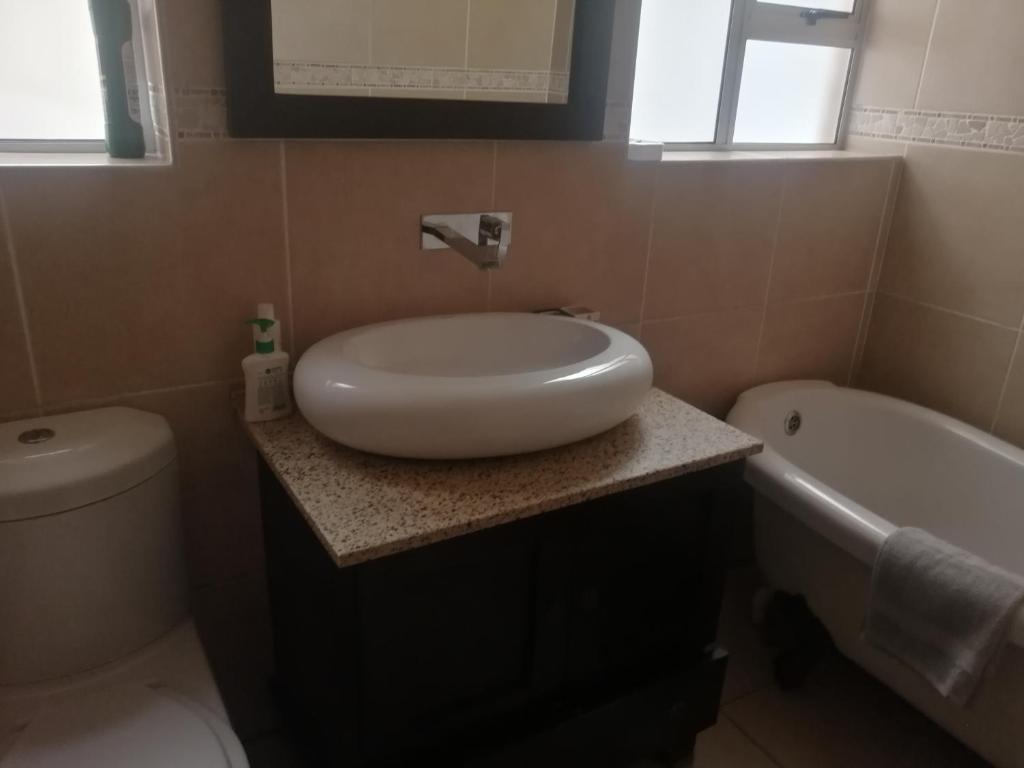 a bathroom with a sink and a toilet and a tub at Home away from home in Cape Town