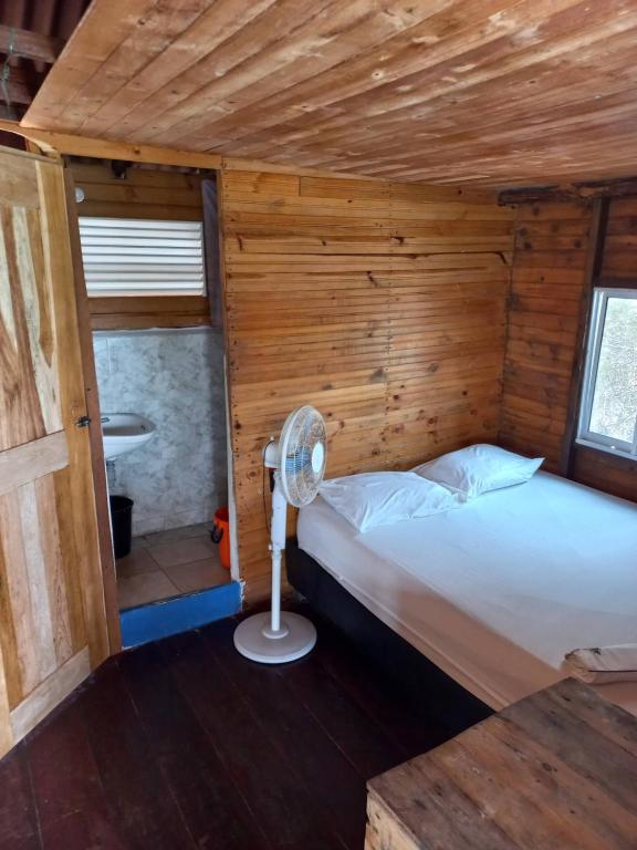uma cama num quarto de madeira com uma ventoinha em Hugos Place Baru em Cartagena das Índias