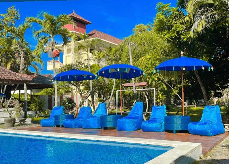 a group of blue chairs and umbrellas next to a pool at New Mekar Jaya Hotel in Legian