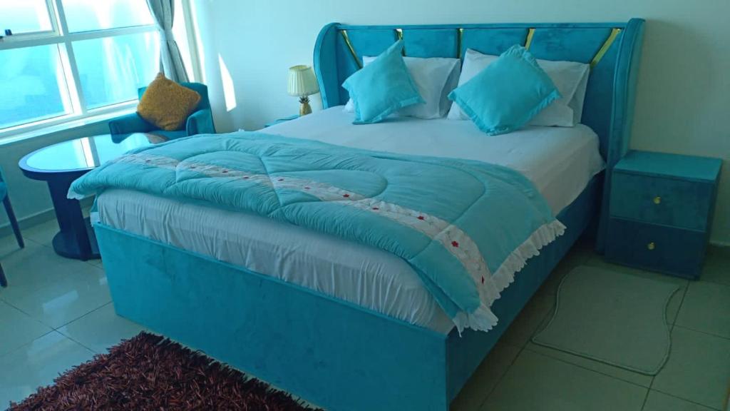 a bedroom with a blue bed with blue pillows at FT22 R3 Open beach ajman washroom is outside in Ajman 