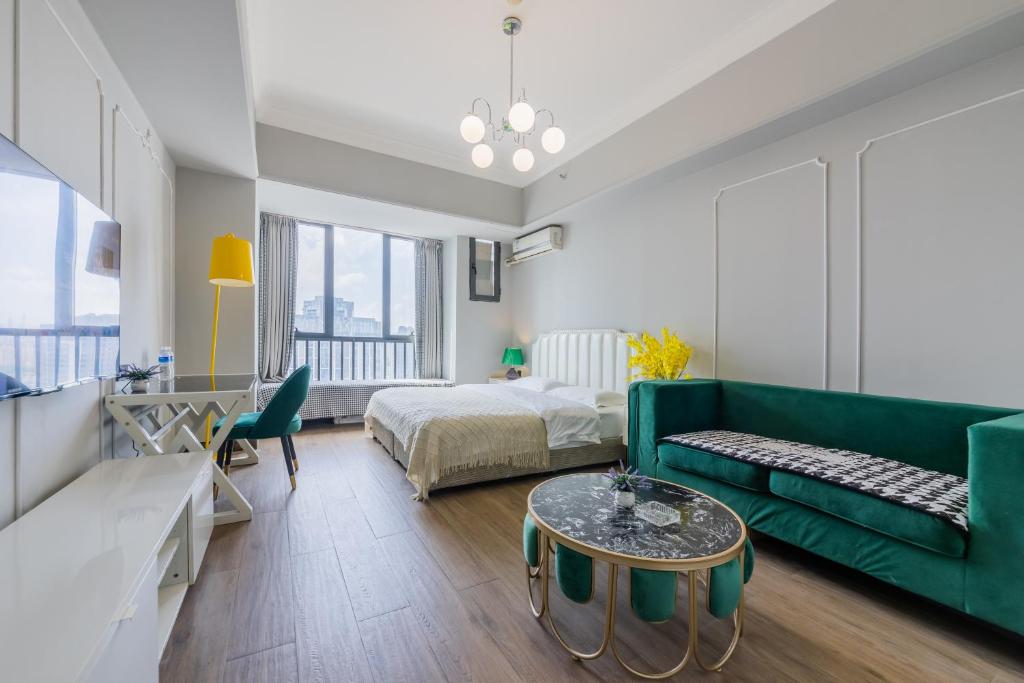 a living room with a green couch and a bed at Lavender Apartment in Guangzhou