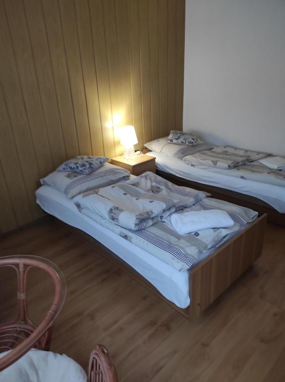 two beds in a room with a table and a lamp at Agroturystyka u Zosi in Żegiestów