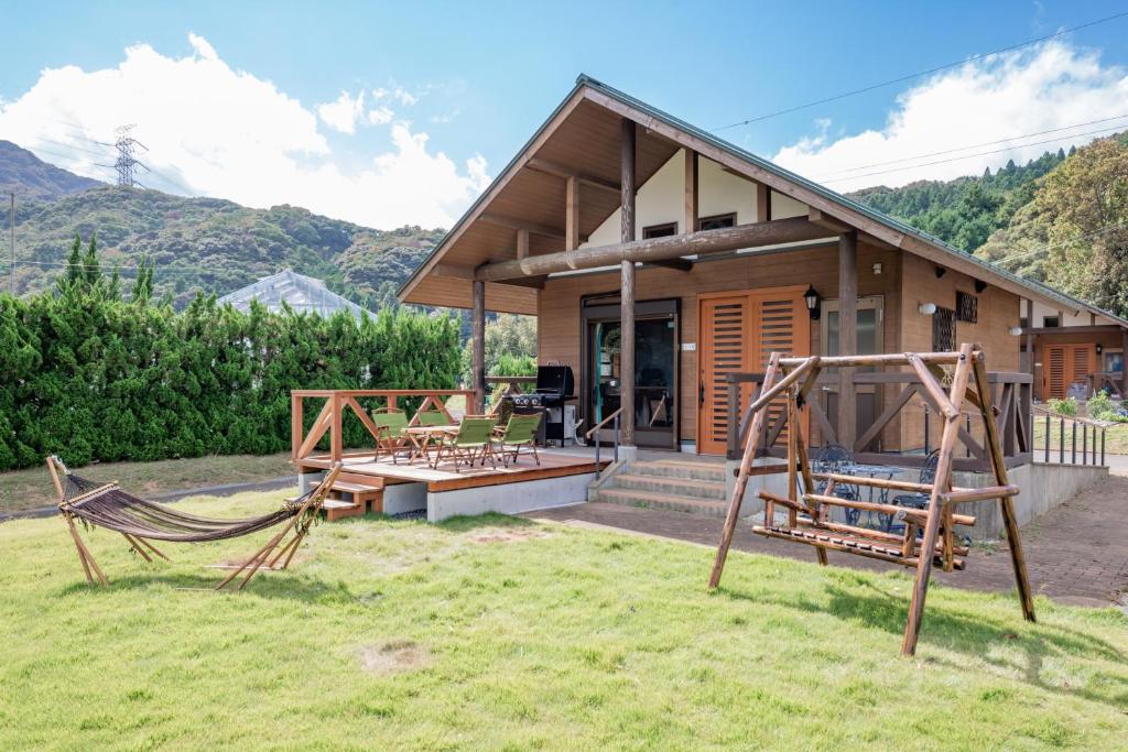 a house with a hammock in front of it at 舞鶴ふるるファームコテージ in Maizuru