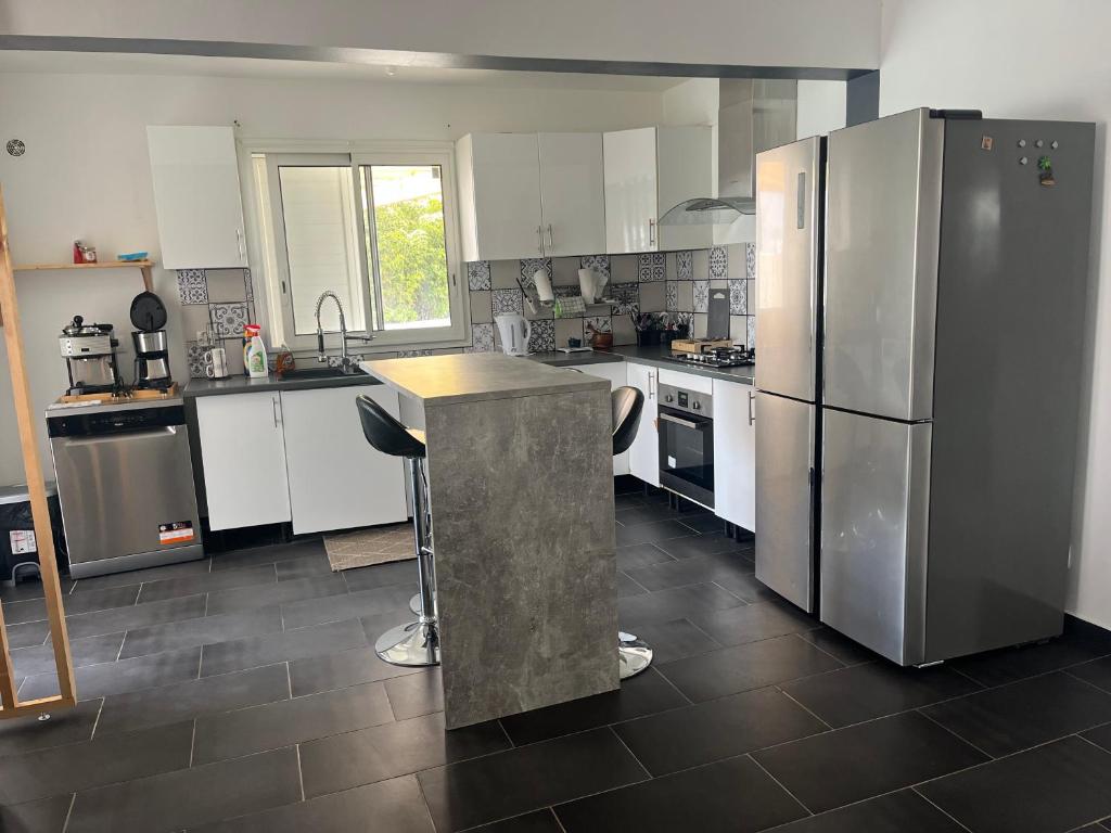 a kitchen with white cabinets and stainless steel appliances at Villa Bois Court 3 chambres in Le Tampon