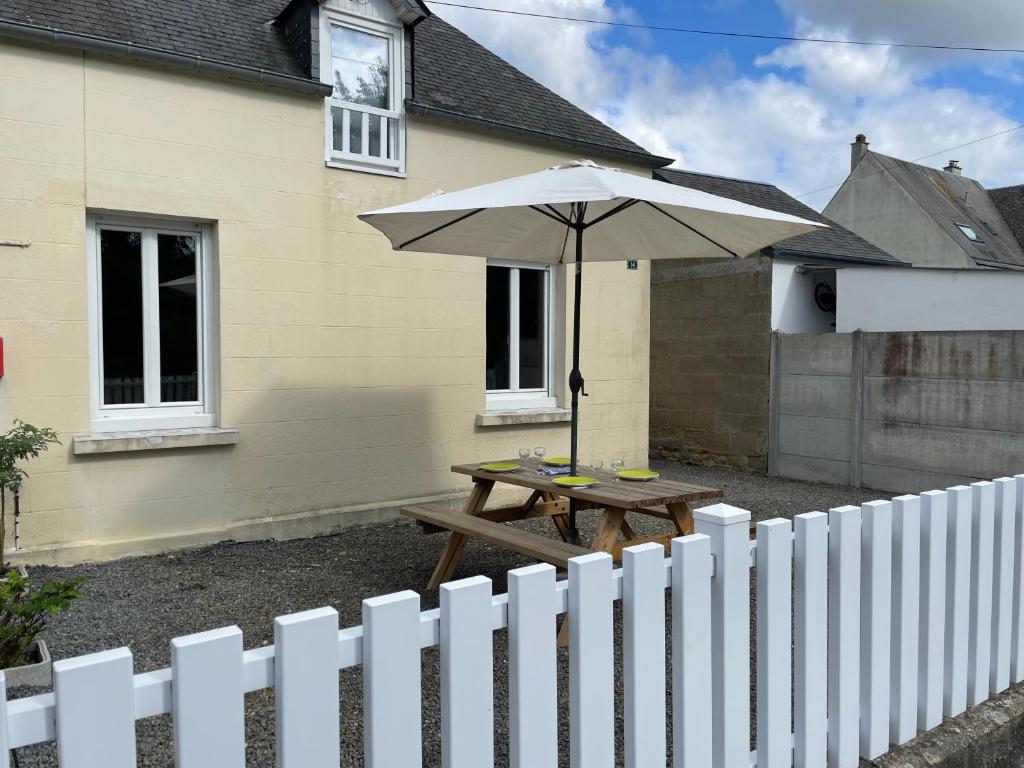 a picnic table with an umbrella in front of a house at Maison gîte 2/4 P baie du mont in Pontorson